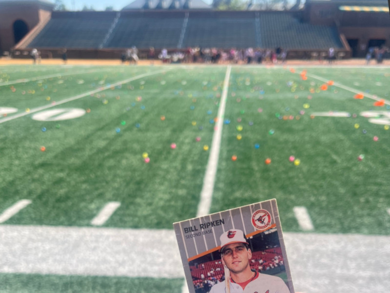 [Image: Billy Ripken card at the 25 yard line of William & Mary's Zable Stadium. Brightly colored easter eggs are seen strewn all over the football field and an out of focus crowd of eager children wait for the starting gun on the other sideline.]