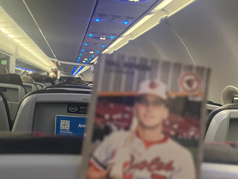 [Image: Interior shot of an A321 with a Billy Ripken card held in the foreground. Lots of occupied headrests visible.]