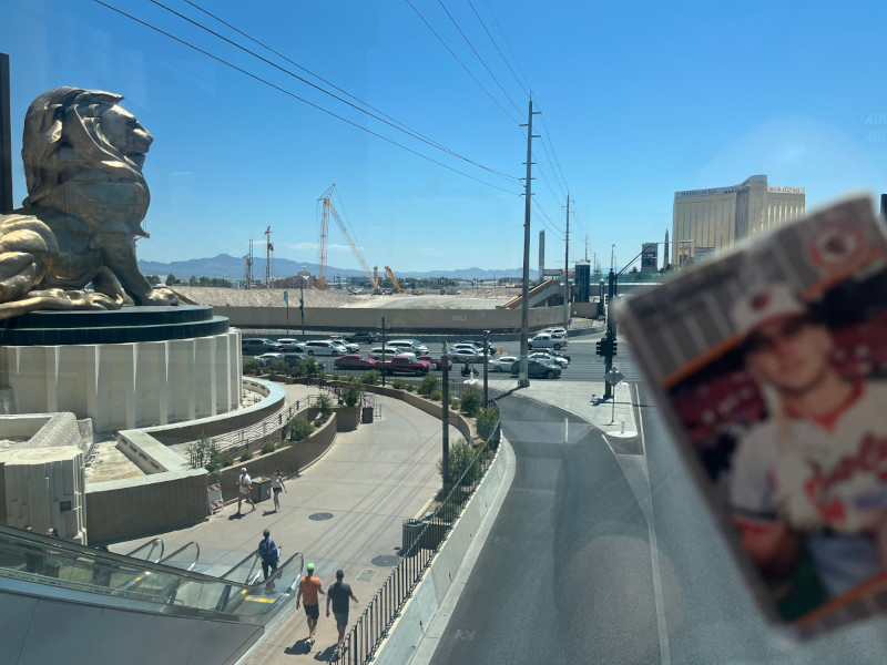 [Image: Wallet card overlooking the construction site of the future Las Vegas A's stadium. The MGM lion statue sits in the foreground. Beyond it is a walled off construction site willed with graded dirt and rising construction cranes.]