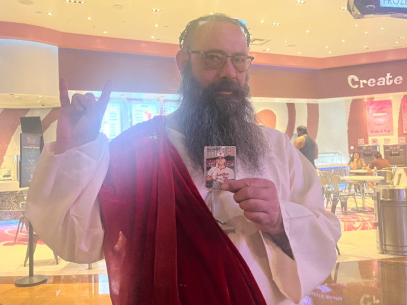 [Image: A cosplaying Jesus holds the Billy Ripken card while standing in front of a frozen yogurt shop in the MGM Food Court.]