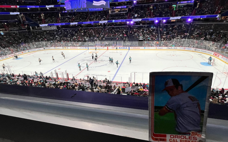 [Image: Cal Ripken card sitting against the 200 level glass watching the Sirens defeat the Victoire.]