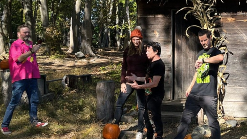 [Image: Hocus Pocus actors discussing their filming experiences at Salem's Pioneer Village. Larry Bagby is walking into frame on the left in a pink shirt. Vinessa Shaw is listening to Jason Marsden explain how characters were instructed to walk in a scene, while Omri Katz checks his watch on the right.]